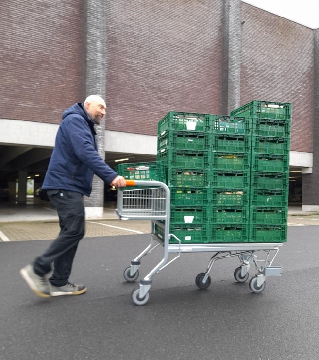 man van de voedselploeg met kar met bakken groenten